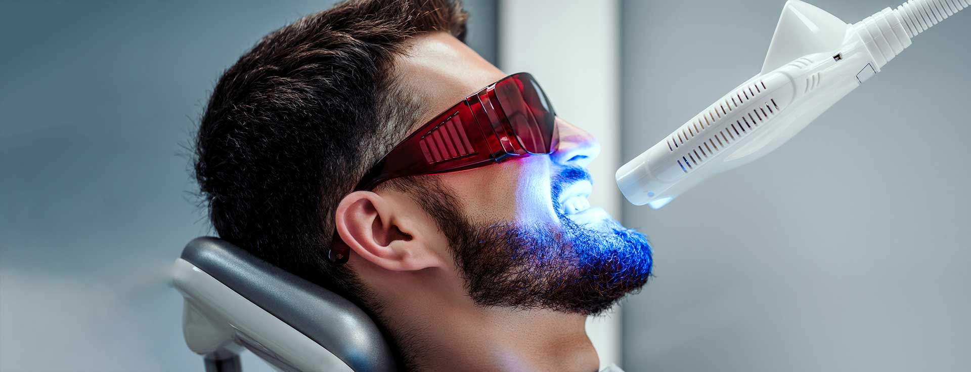 A male patient is getting teeth whitening treatment at the dentist